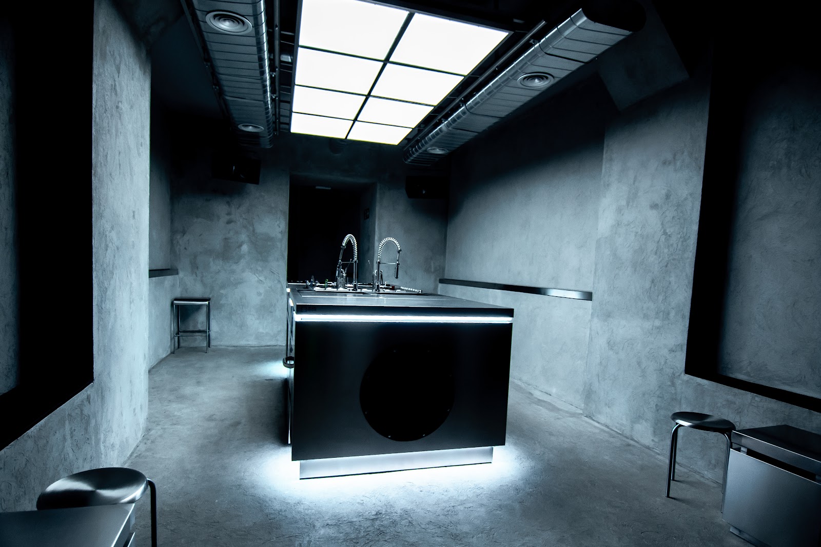 Interior industrial de Kinki Cocktail Club: barra negra central, paredes de hormigón, iluminación LED