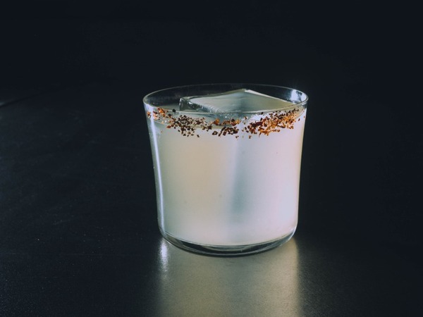 Margarita del Sol cocktail in a tumbler with gold rim and tropical garnish