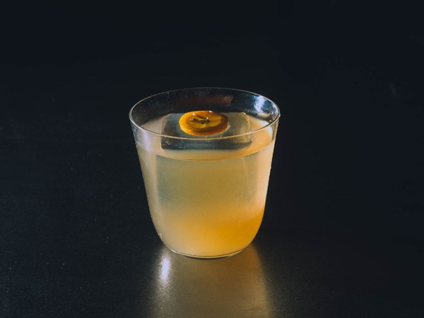 Smoked Penicillin — cóctel de whisky ahumado con kumquat sobre fondo oscuro