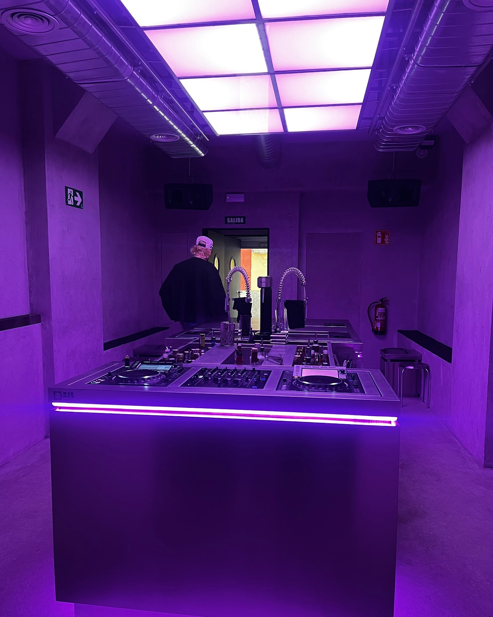 KINKI Cocktail Club DJ booth with neon lighting, raw concrete walls and dramatic purple-lit atmosphere in Malasaña