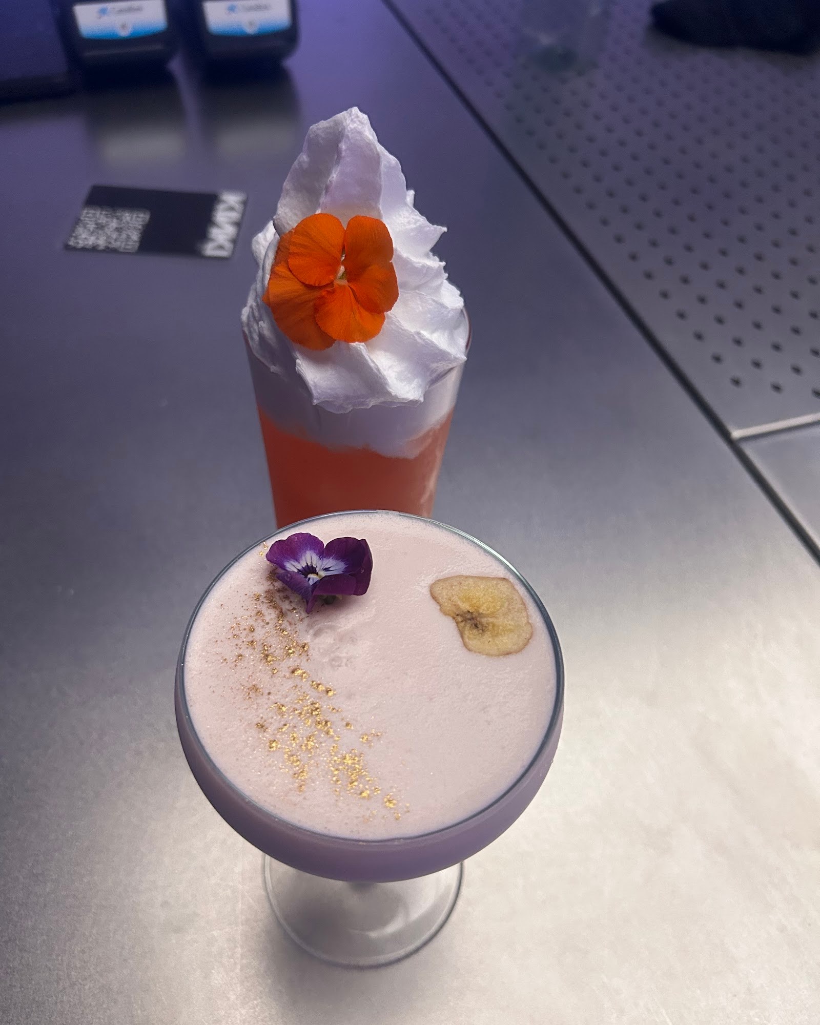 Two artisanal cocktails with edible flowers, premium presentation at KINKI Cocktail Club