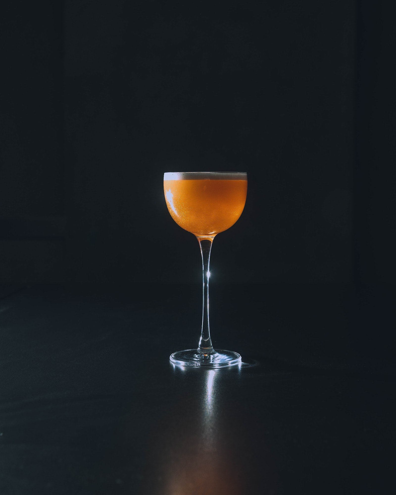 Amber cocktail in a dark atmospheric bar setting at KINKI Cocktail Club