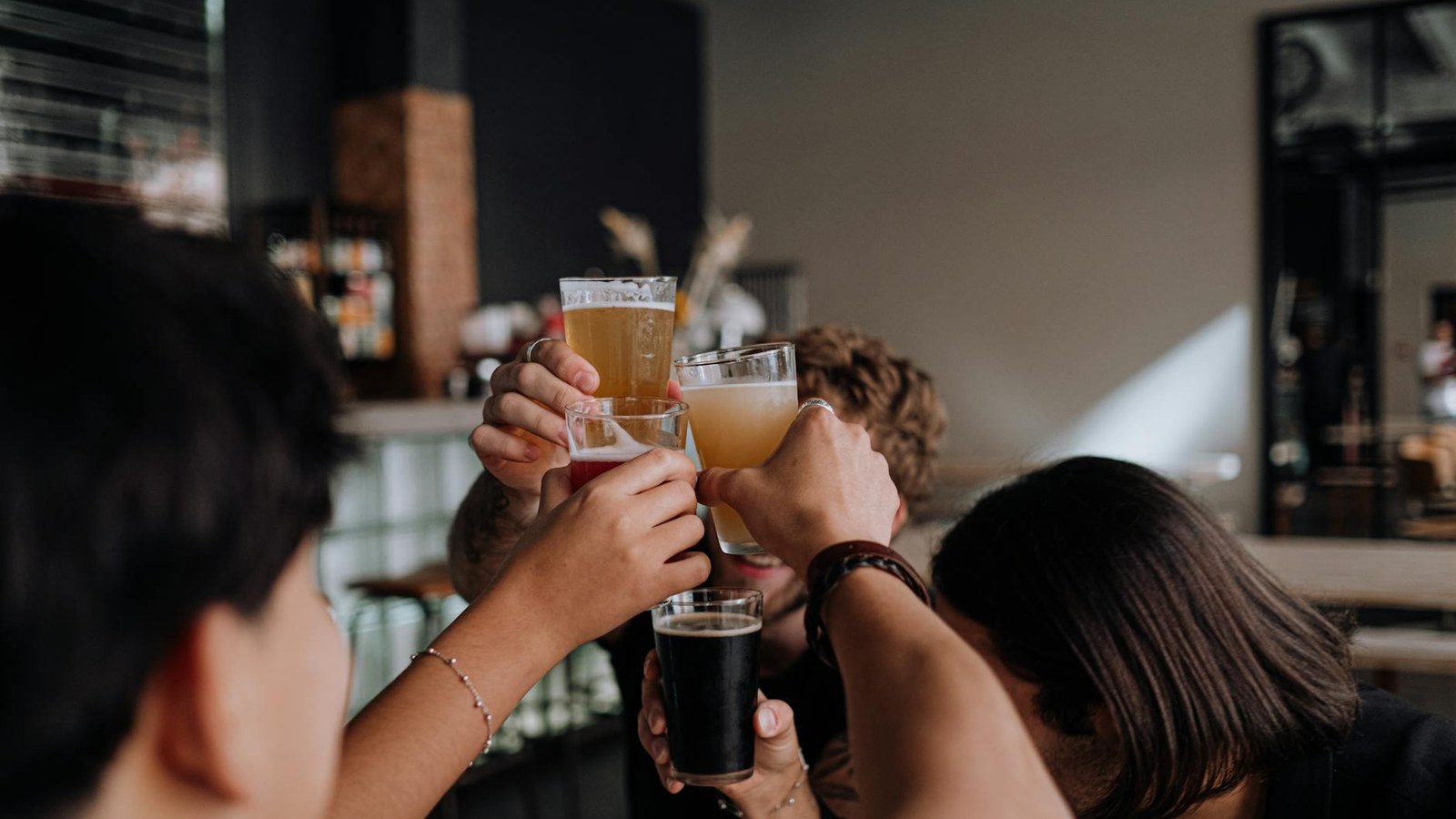 Group of friends clinking glasses and celebrating at a bar